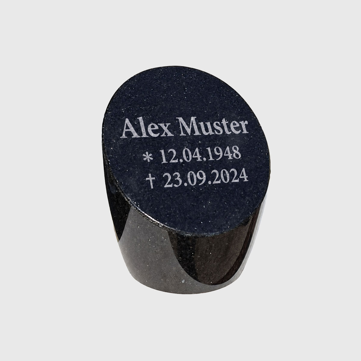 Ovaler Gedenkstein mit der Musterinschrift Alex Muster und fiktiven Geburts- und Sterbedaten